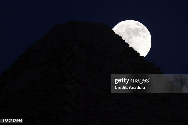 View of the Full Moon behind the Pyramids of Giza in Egypt on July 02, 2023.