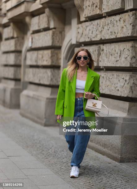 Sonia Lyson is seen wearing Miu Miu x New Balance white denim 574 sneaker, Boss blue denim jeans, Louis Vuitton mini twist leather beige bag, Versace...