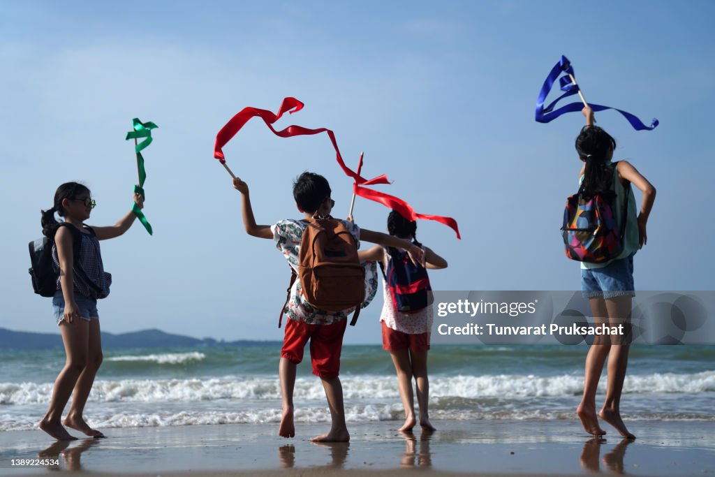 Playful children playing , running and laughing together on the beach .
