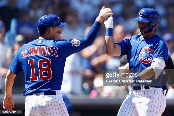 Seiya Suzuki of the Chicago Cubs high fives Frank Schwindel after hitting a two-run home run against the Los Angeles Angels during the fourth inning...