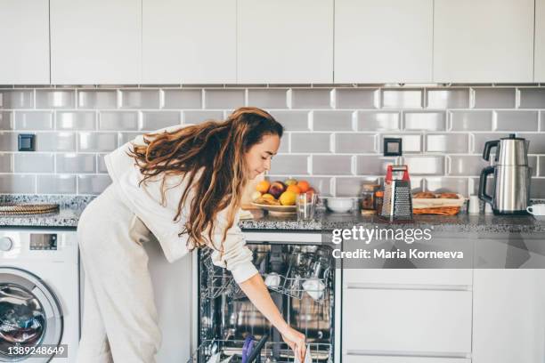 woman putting dishes in dishwasher. - spülmaschine stock-fotos und bilder