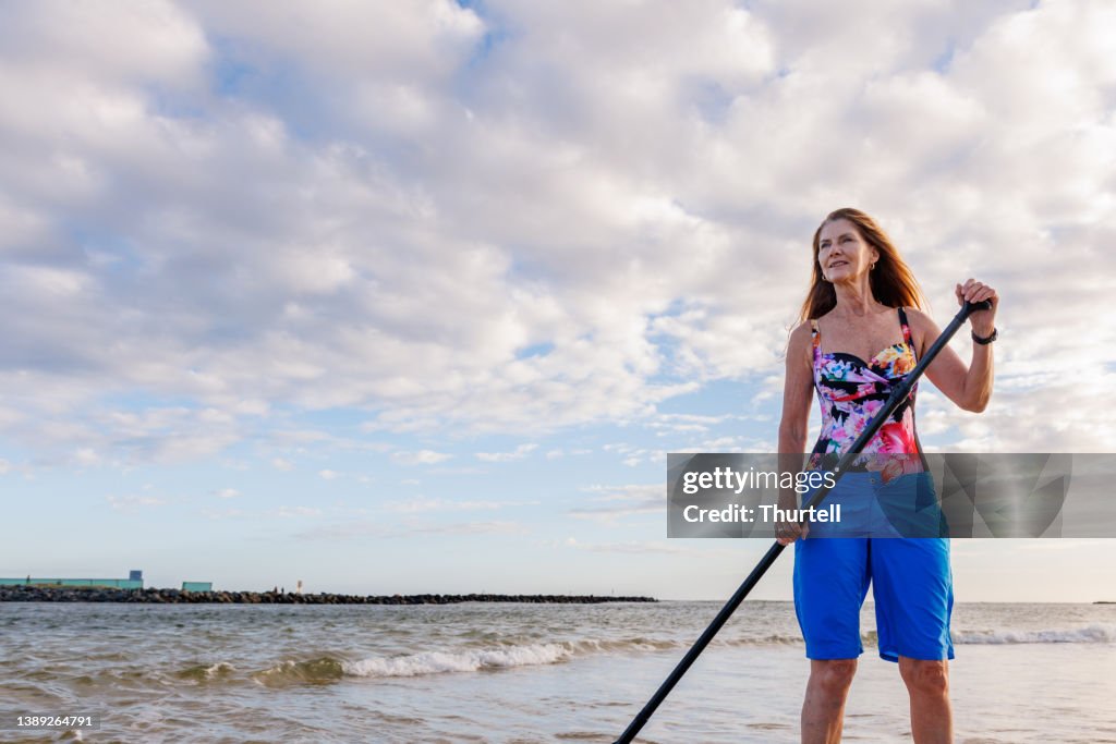Mature Australian Woman Using Stand Up Paddle Board In The Early ...