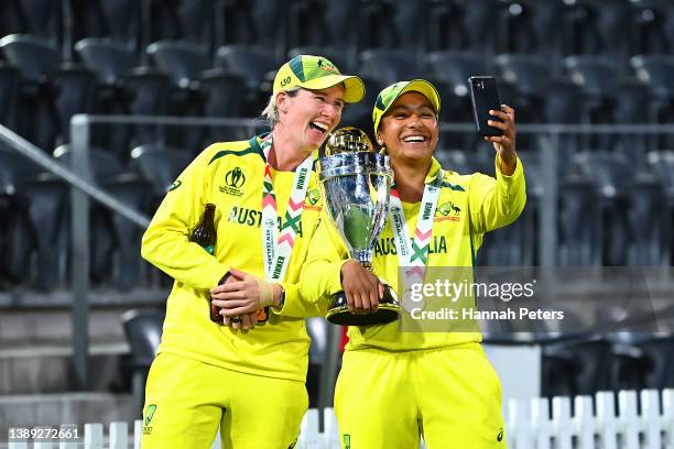 Beth Mooney and Alana King of Australia take selfies with the trophy after Australia won the 2022 ICC Women's Cricket World Cup Final match between...