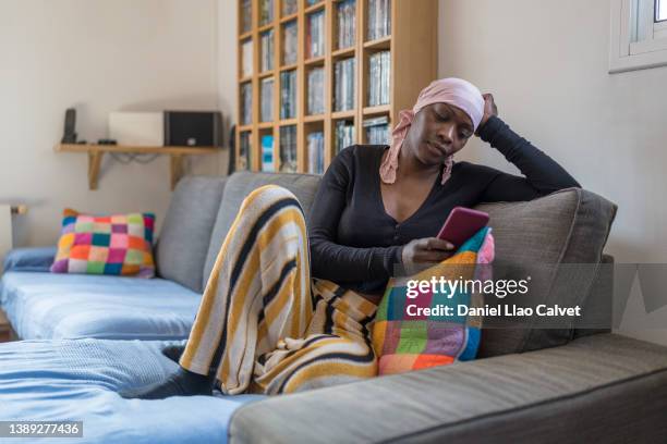 woman with cancer reading text messages at home - cellphone cancer illness stock pictures, royalty-free photos & images