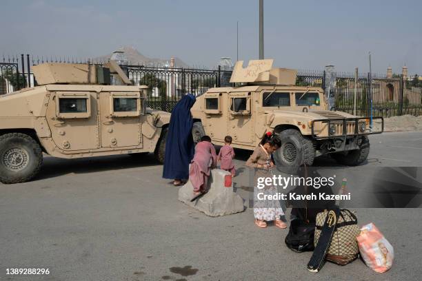 Cricket bat rests on the belongings of a family waiting for transport near abandoned Humvee military trucks left behind by the departing US military...