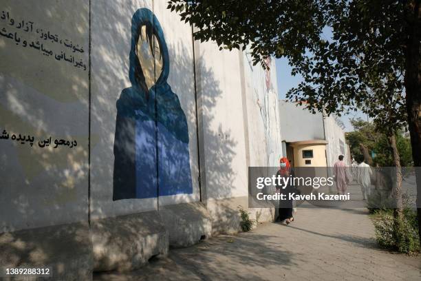 Woman in veil goes past a mural painted on the heavily fortified wall of ministry for women's affairs on September 20, 2021 in Kabul, Afghanistan.