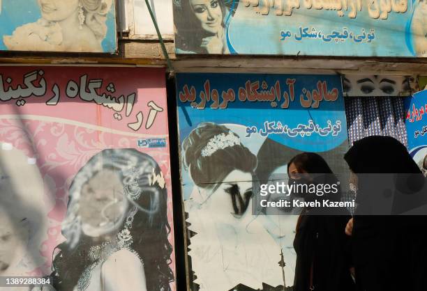 Defaced faces of women appear on the windows of hair and beauty salons on the airport road on September 19, 2021 in Kabul, Afghanistan. For the fear...