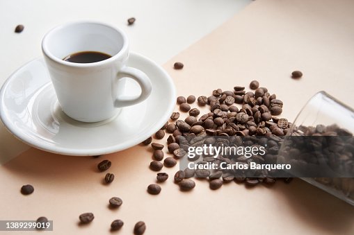 Close up photo of black coffee cup and dropped coffee beans. Close up photo of black coffee cup and dropped coffee beans.