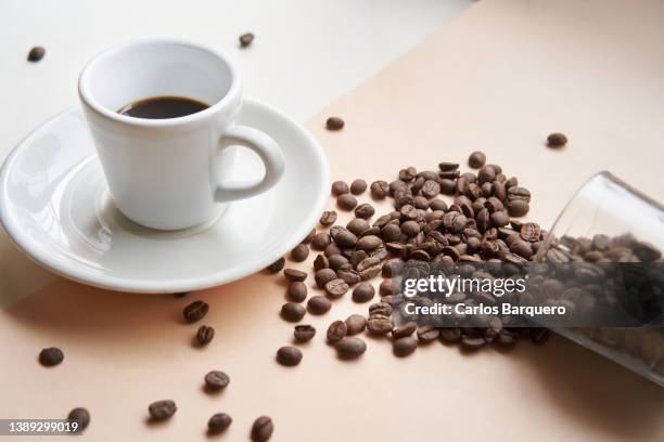 close up photo of black coffee cup and dropped coffee beans. - decaffeinated stock pictures, royalty-free photos & images