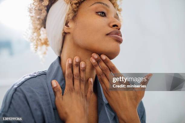 pretty woman applying face cream on her neck - touching stock pictures, royalty-free photos & images