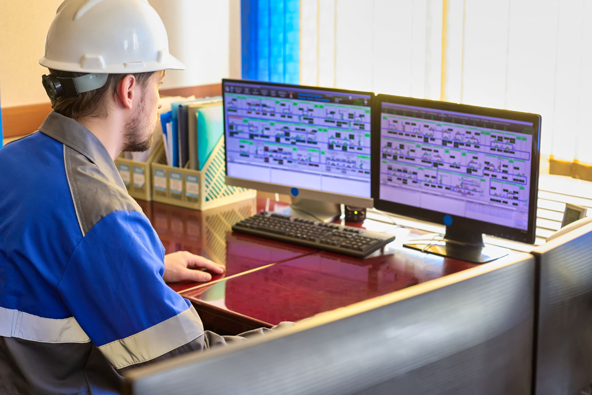 Worker in overalls uses a linear telemechanics system to control the technological processes of the enterprise. Automated workplace of a dispatcher or operator of a modern enterprise