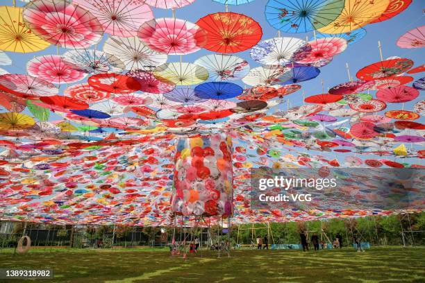 Tourists stand under colorful paper umbrellas at a park during Qingming Festival Holiday on April 3, 2022 in Xiangyang, Hubei Province of China.