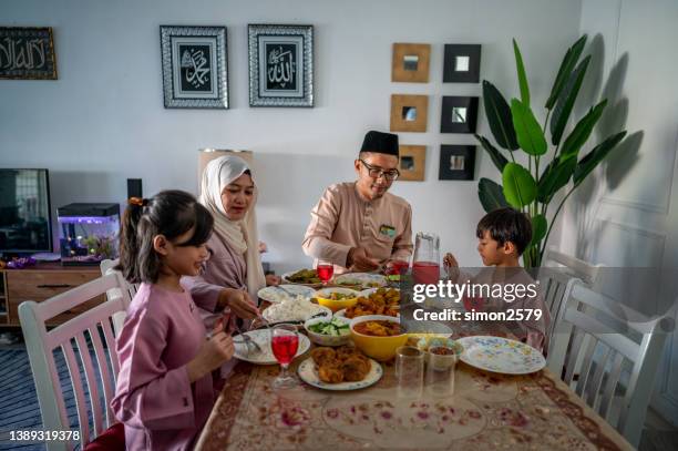 muslim family gathering and eating together during eid-fitr celebration - malayan ethnicity stock pictures, royalty-free photos & images