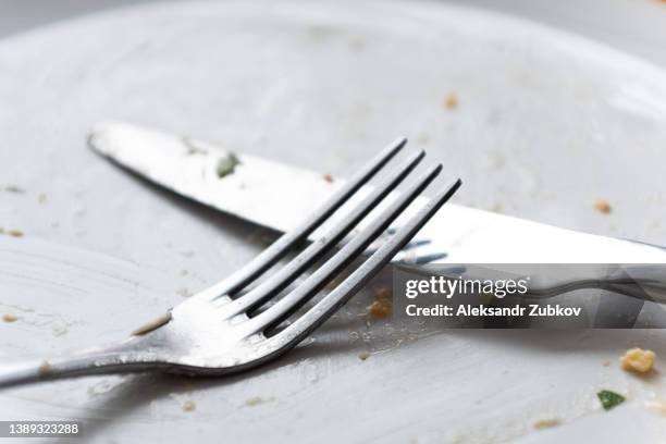 a dirty empty plate, fork and knife on a wooden table. used cutlery, symbolizing the end of lunch or dinner. - cleaning after party fotografías e imágenes de stock