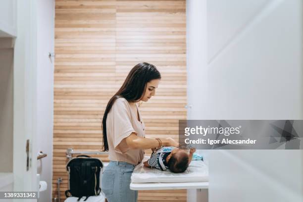 お母さんがおむつ替え台の上で赤ちゃんのおむつを替える - changing diaper ストックフォトと画像