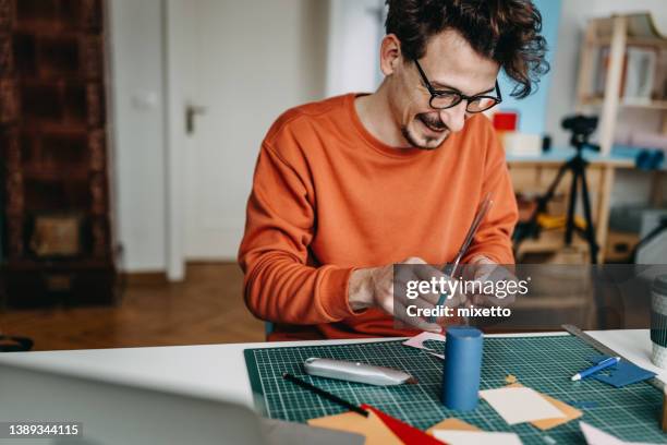 diseño masculino profesional de papeles de corte en escritorio en estudio - esterilla para cortar fotografías e imágenes de stock