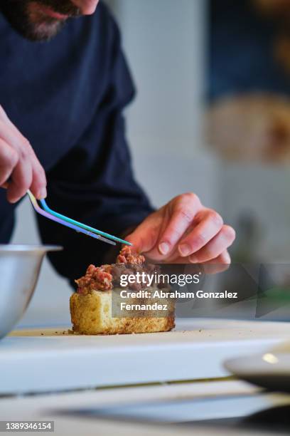 chef using a tweezers to accommodate ground beef on piece of toast - filet americain stockfoto's en -beelden