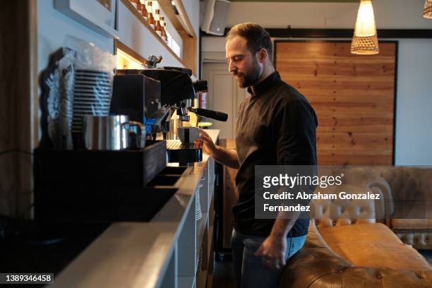 adult man making coffee on machine of restaurant - bar cafeteria fotografías e imágenes de stock