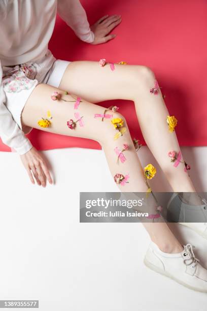 crop slim woman with flowers stuck to legs - sticky buds photos et images de collection
