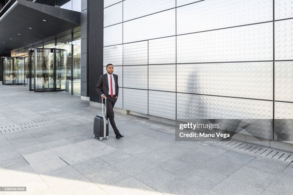 Confident businessman carrying a suitcase while walking outdoors in financial district.