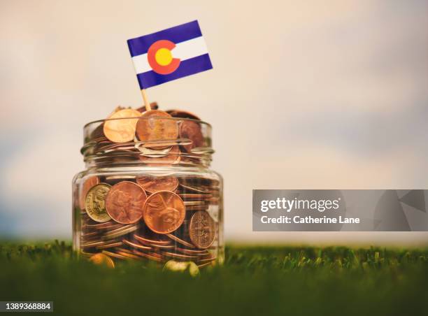 savings jar filled with american currency with a colorado flag - crowdfunding stockfoto's en -beelden
