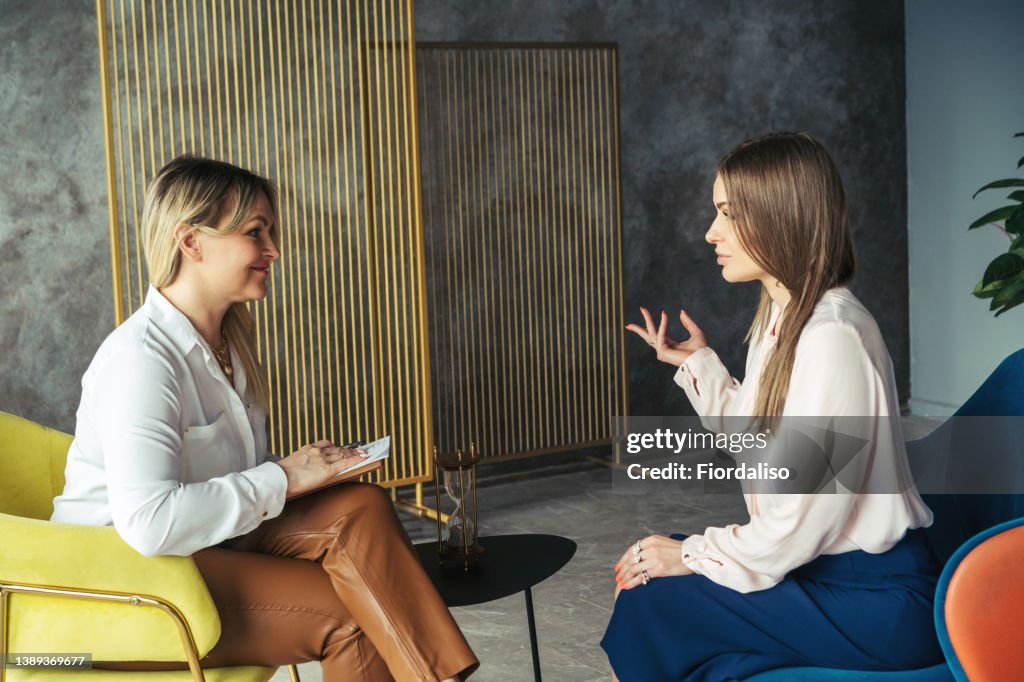 Woman psychologist talking to patient girl