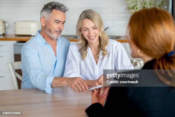 happy mature couple meeting investments and financial advisor at home - inheritance consulting stockfoto's en -beelden