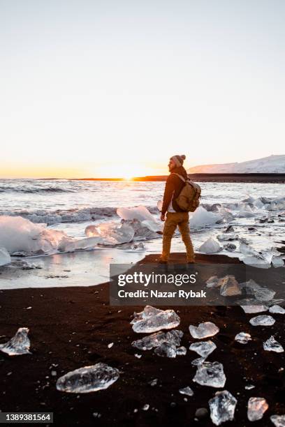 アイスランドのダイヤモンドビーチで夕日を楽しむ男 - jokulsarlon lagoon ストックフォトと画像