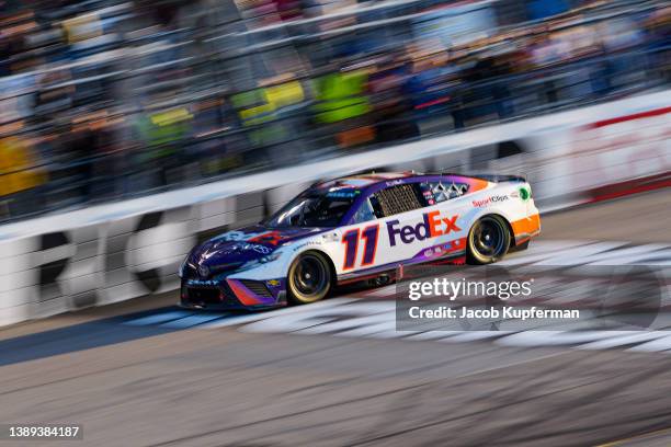 Denny Hamlin, driver of the FedEx Express Toyota, crosses the finish line to win the NASCAR Cup Series Toyota Owners 400 at Richmond Raceway on April...