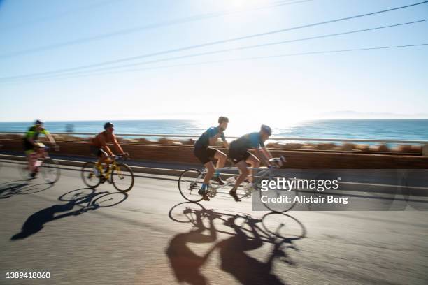 cyclists racing together at dawn in a large scale cycle event - tandem bicycle stockfoto's en -beelden