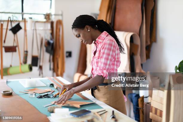 female small business owner working in her leatherwork studio - mode ontwerper stockfoto's en -beelden