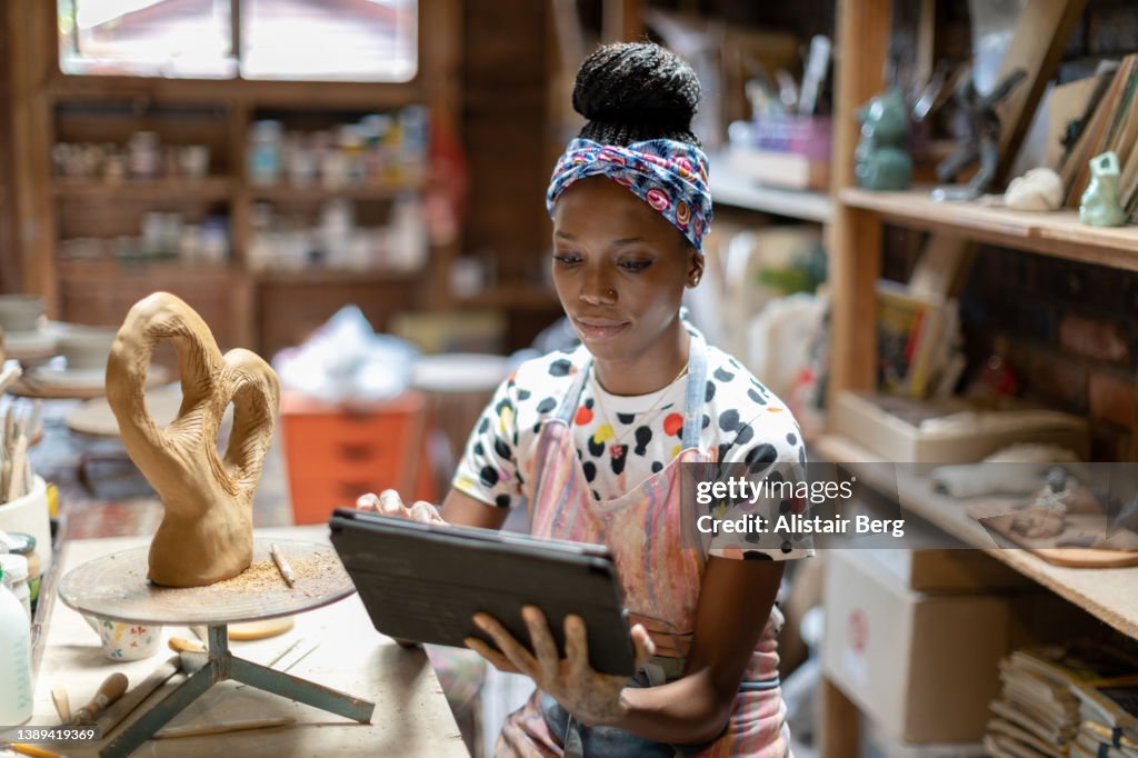 Female sculptor using a digital tablet in her art studio