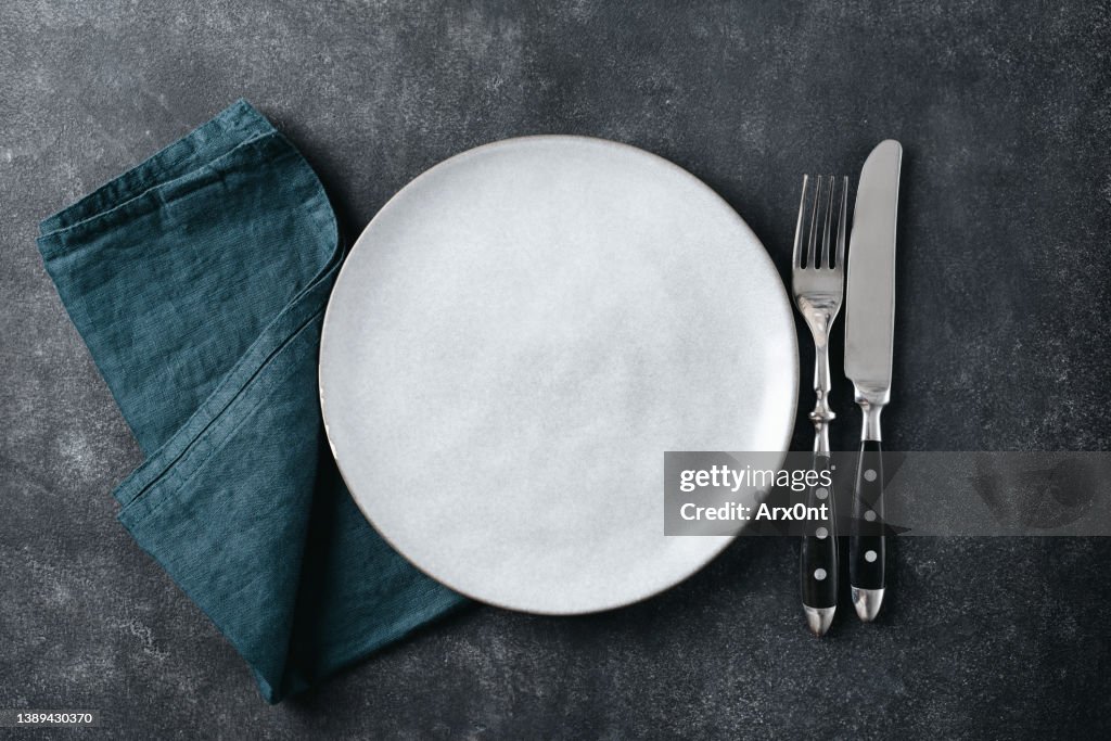Modern table setting with empty plate, cutlery and linen table cloth