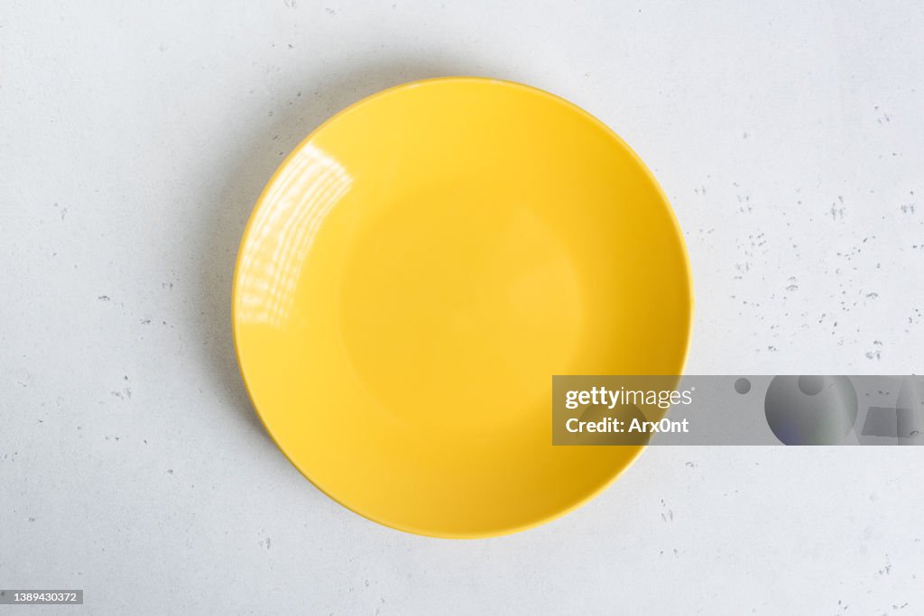 Empty yellow plate on grey concrete table background