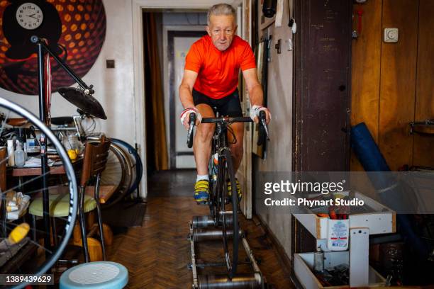 senior man athlet radfahren zu hause, sportler training mit rennrad zu hause - house old bike stock-fotos und bilder