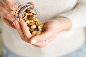 Nuts spilling from jar in woman's hand