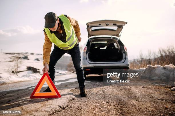 senior man putting warning triangle sign on a road - reflexkläder bildbanksfoton och bilder