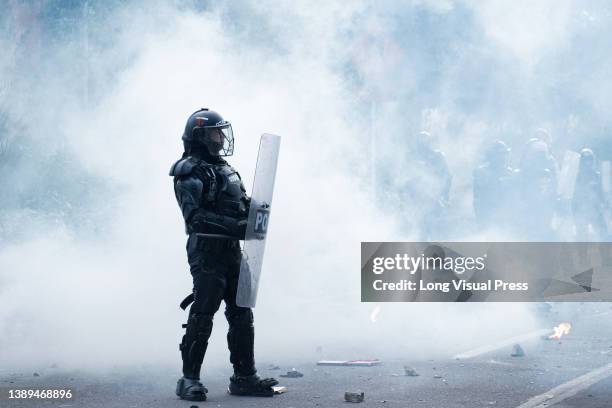 Colombia's riot police officer 'ESMAD' is seen inside a cloud of tear gas as students protested against Colombia's national police and government on...