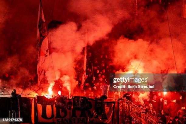 Fans of St. Pauli burn flares during the Second Bundesliga match between FC Hansa Rostock and FC St. Pauli at Ostseestadion on April 02, 2022 in...