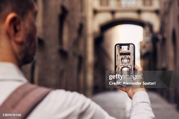rear view of a man photographing street in barcelona with a smartphone, barcelona, spain - augmented reality phone stock-fotos und bilder