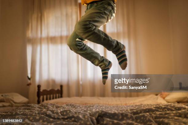 saltar en la cama - a boy jumping on a bed fotografías e imágenes de stock