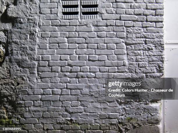 brick and stone wall painted gray and illuminated by street lights in brussels - wall night stock-fotos und bilder