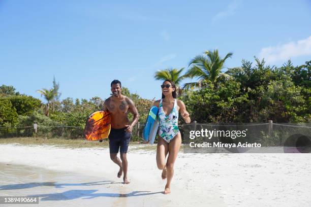 a multiracial millennial couple play in the clear, turquoise water while wearing bathing suits, on a bright sunny day in a tropical environment. - 40s couple sunny stockfoto's en -beelden