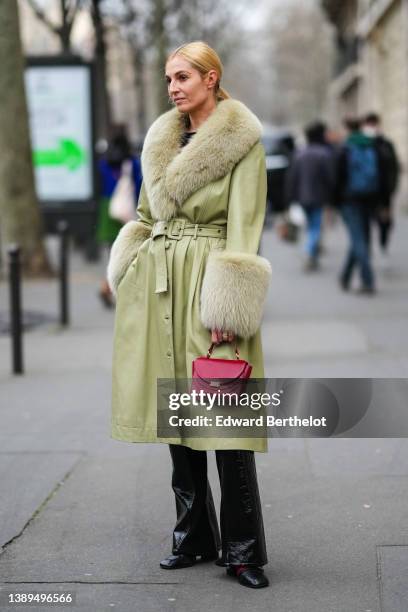 Guest wears a black cut-out t-shirt, a pale green shiny leather with large fur collar and wrists belted coat, black shiny leather varnished flared...