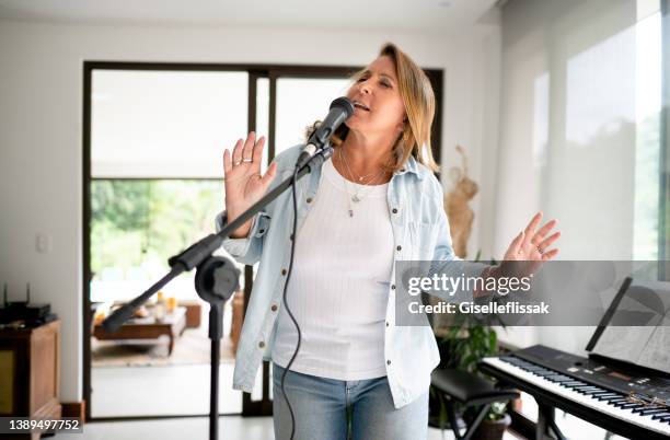 mujer madura cantando en un micrófono en un estudio de grabación casero - keyboard player fotografías e imágenes de stock