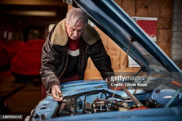 senior man working on engine of vintage sports car - garage home car repair stock pictures, royalty-free photos & images
