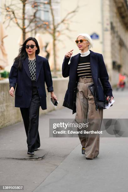 Guest wears sunglasses, a black t-shirt, a white pearls checkered t-shirt, a navy blue blazer jacket, black large suit pants, black shiny leather...