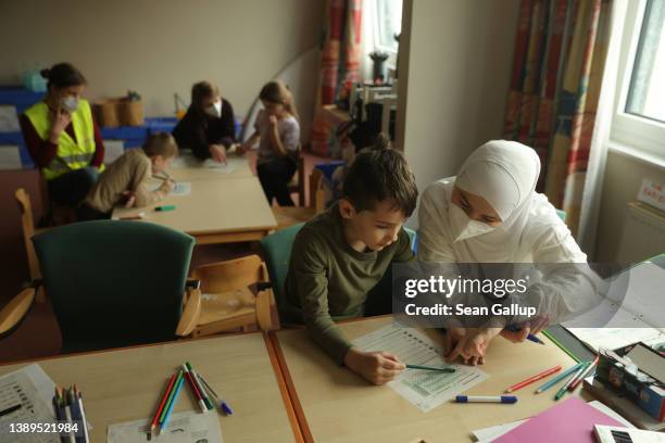 Ukrainian refugees, including Yulia coaxing her son Salman learn German from volunteers at the former hotel that is now their temporary home on April...