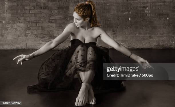 full length of young woman sitting on floor against wall - drake one dance stock-fotos und bilder