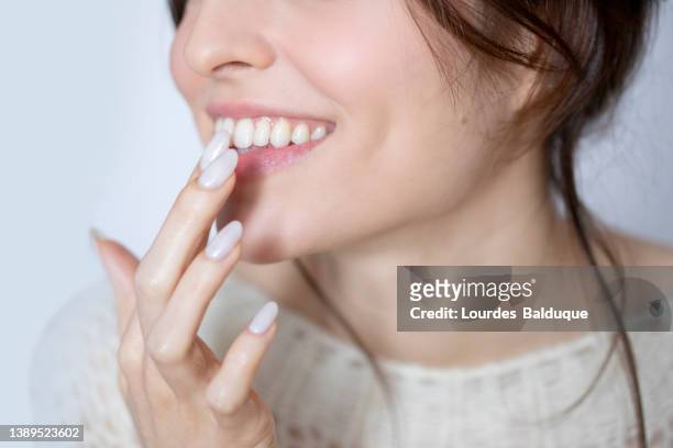 woman applying lip gloss - middle finger stock-fotos und bilder